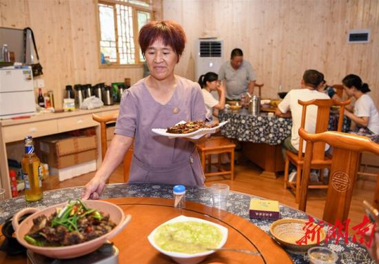（8月12日，沅陵縣官莊鎮(zhèn)界亭驛村金州灣驛站，黃三妹在為客人上菜。）
