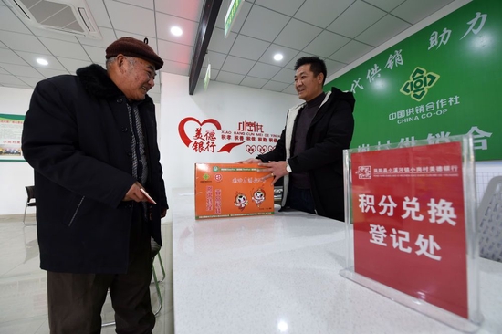 在安徽省滁州市鳳陽縣小崗村，村民繆守魯（左）在村里“美德銀行”用積分兌換生活物品（2021年1月30日攝）。新華社記者 周牧 攝